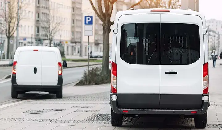 Kaksi pakettiautoa pysäköityinä kadulla