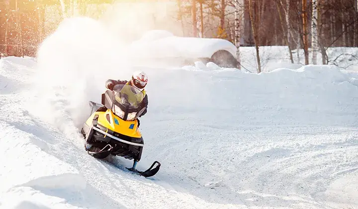 Ihminen ajaa moottorikelkalla lumisella tiellä